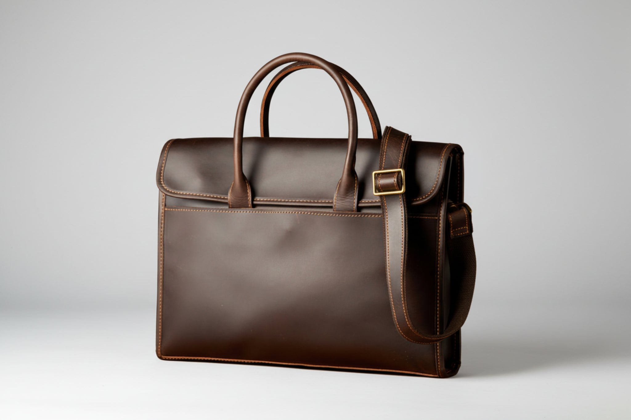 Brown leather briefcase with a gold buckle on a white background