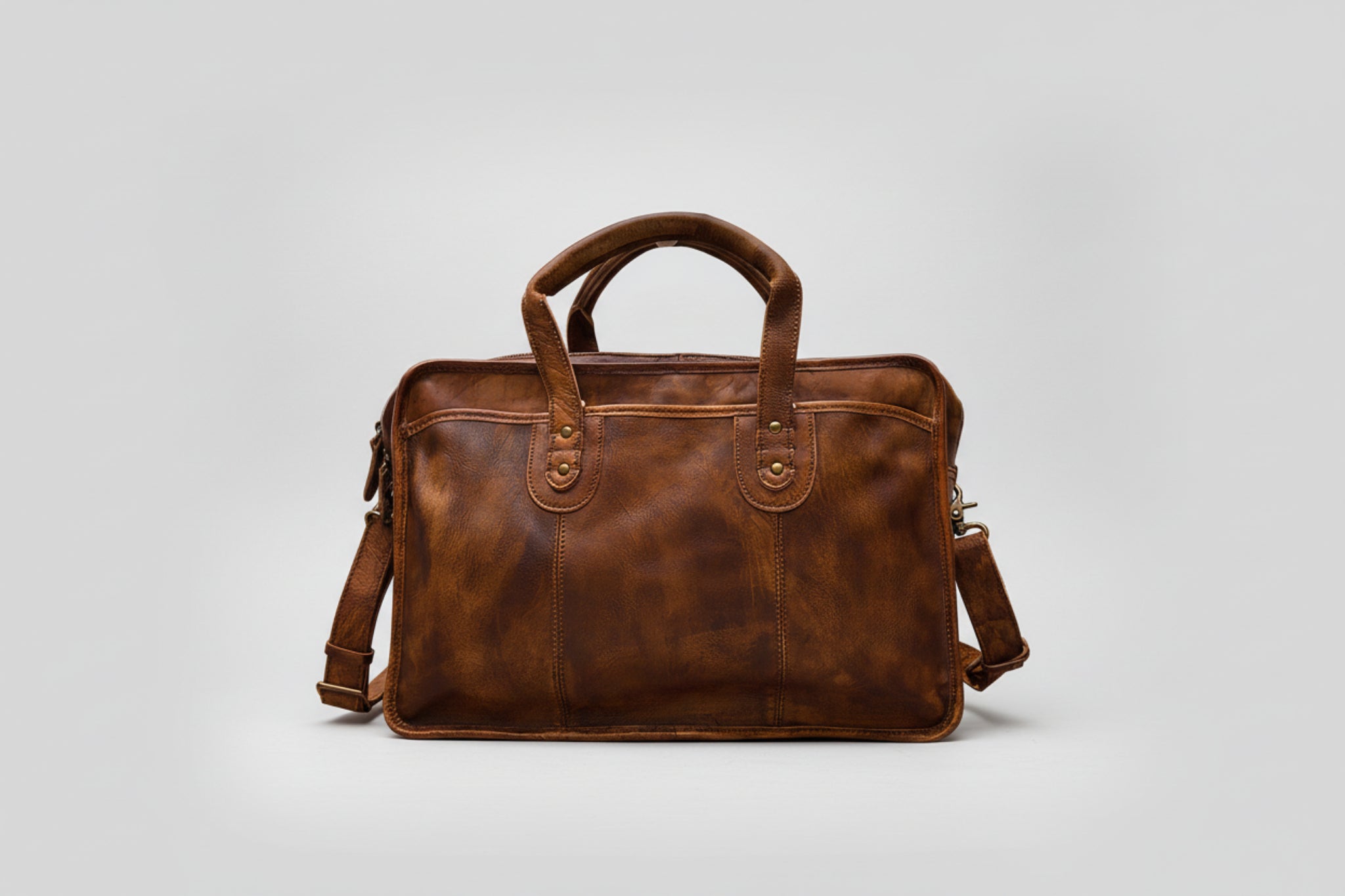Brown leather briefcase with shoulder strap on a white background