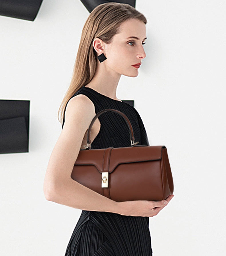 Woman holding a brown handbag against a white background