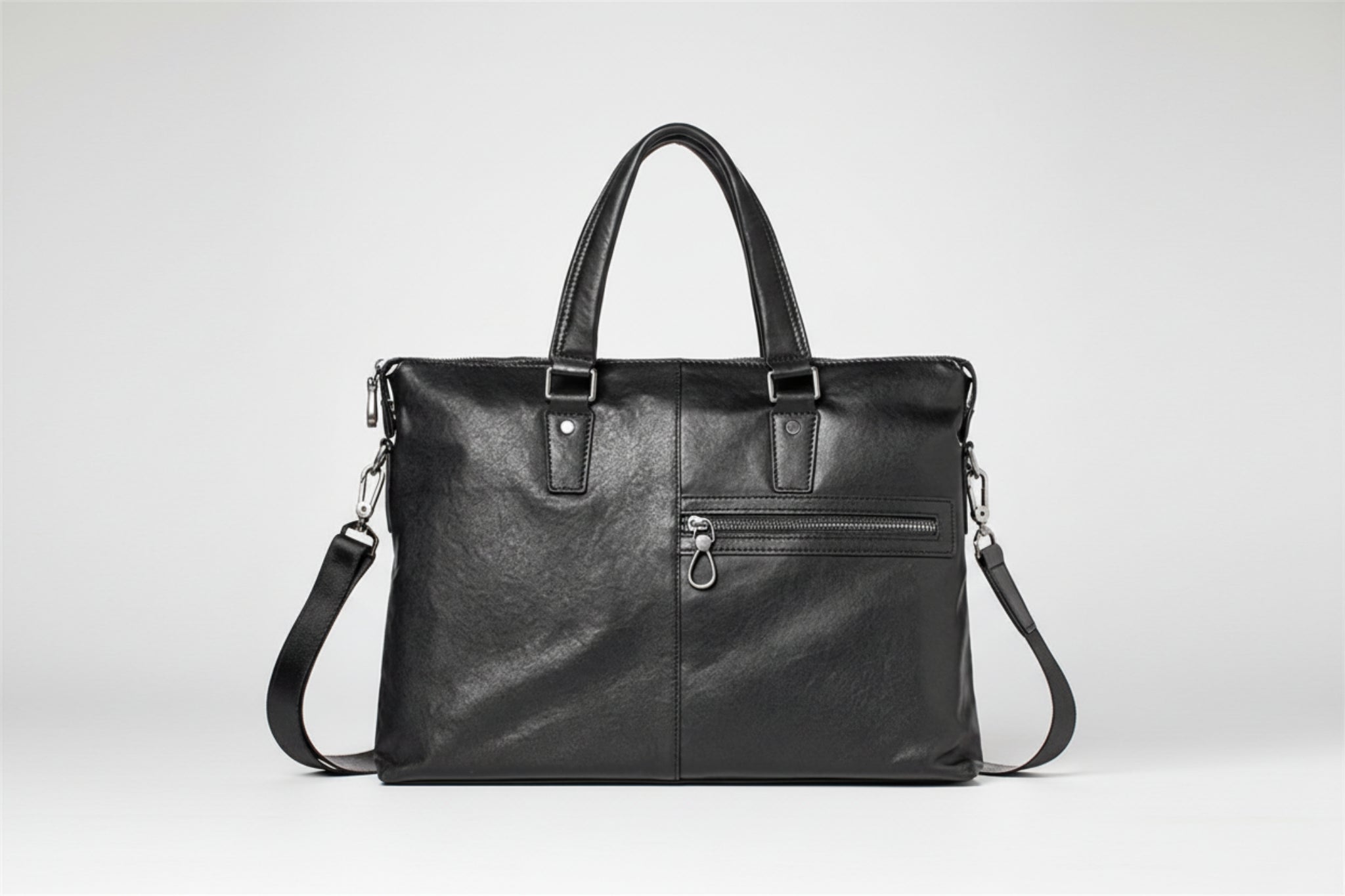 Black leather handbag with multiple zippers on a white background