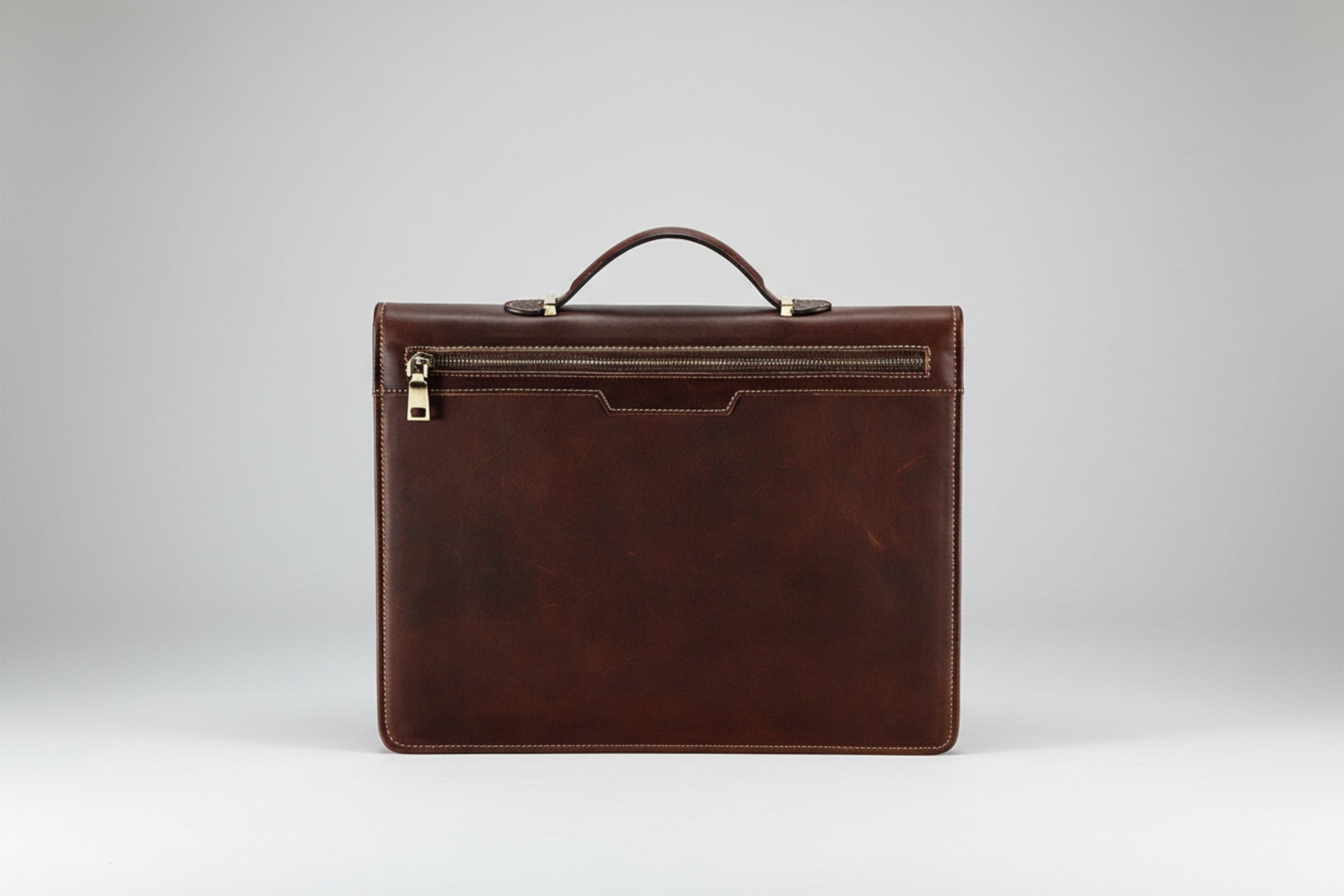 Brown leather briefcase with gold zipper on a white background