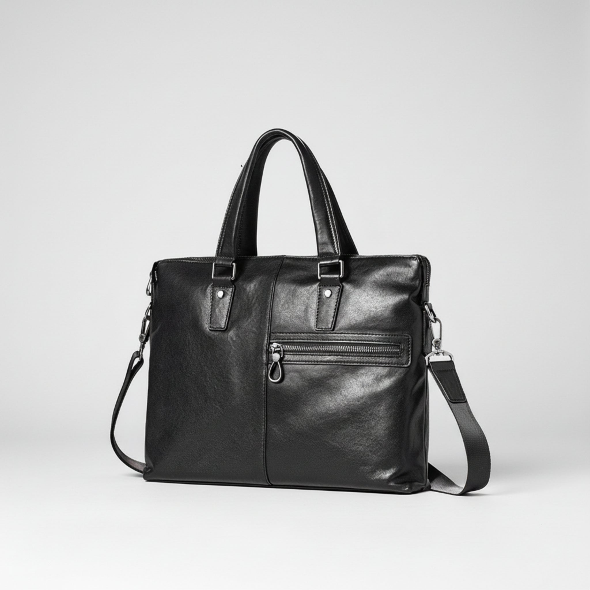 Black leather handbag with shoulder strap on a white background