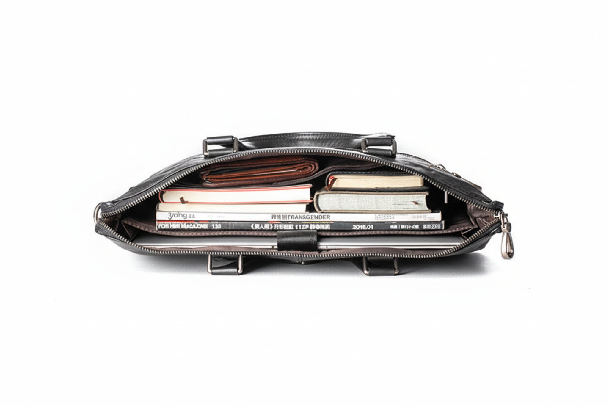 Black leather clutch bag with books and magazines inside on a white background